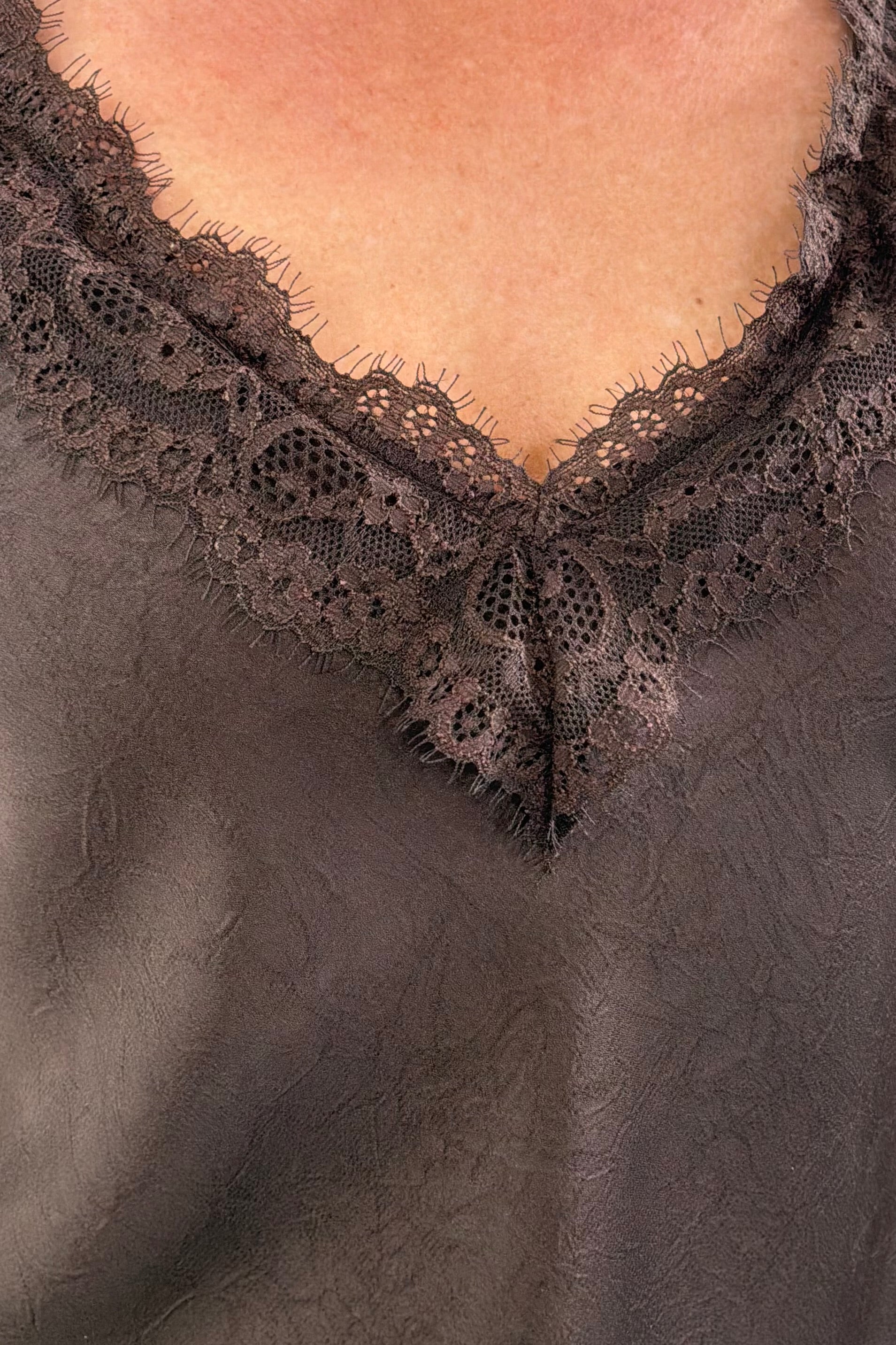 Woman wearing a brown sleeveless top with lace details