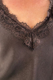 Woman wearing a brown sleeveless top with lace details