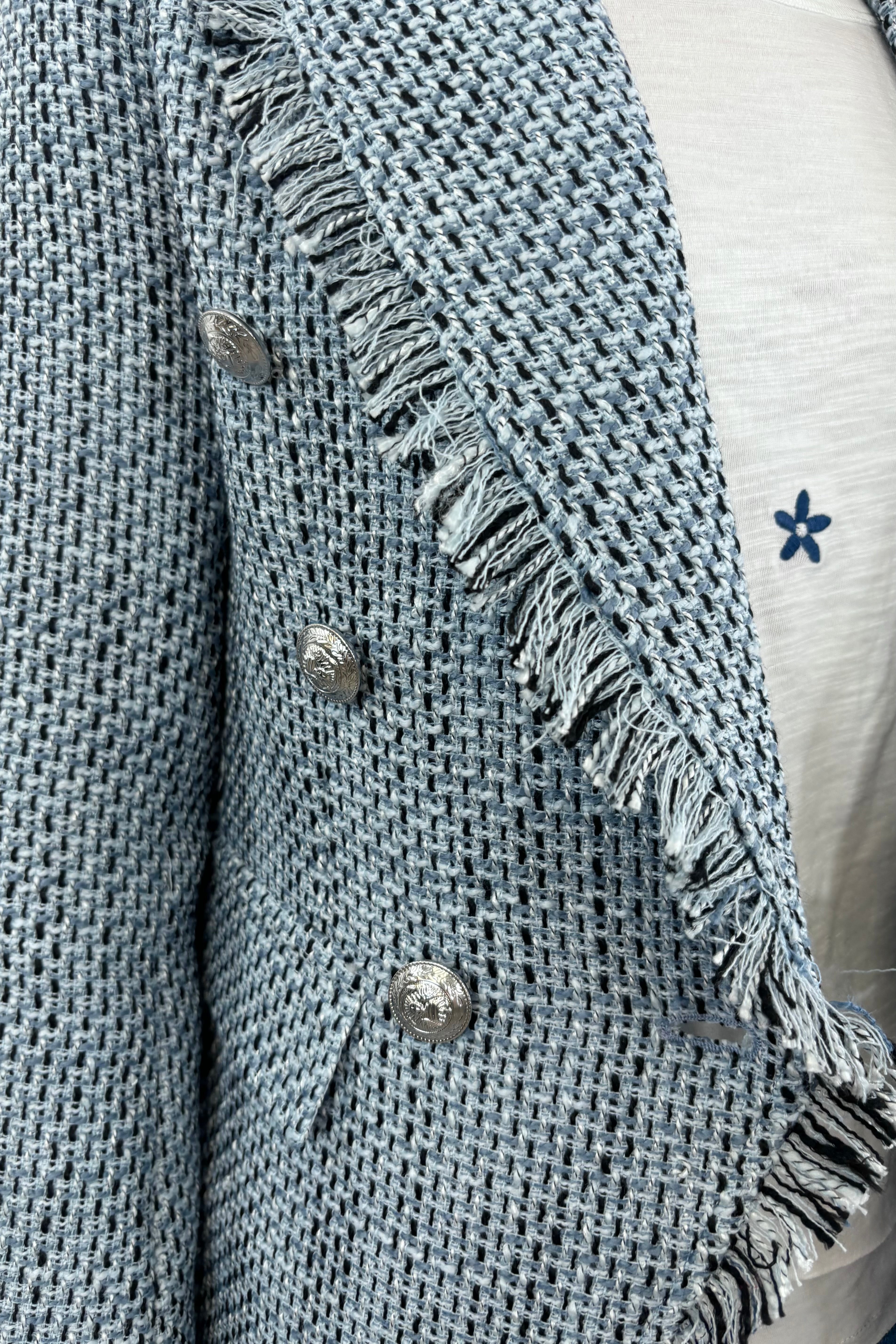Close up of Woman wearing a light blue tweed blazer with silver buttons