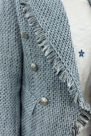 Close up of Woman wearing a light blue tweed blazer with silver buttons