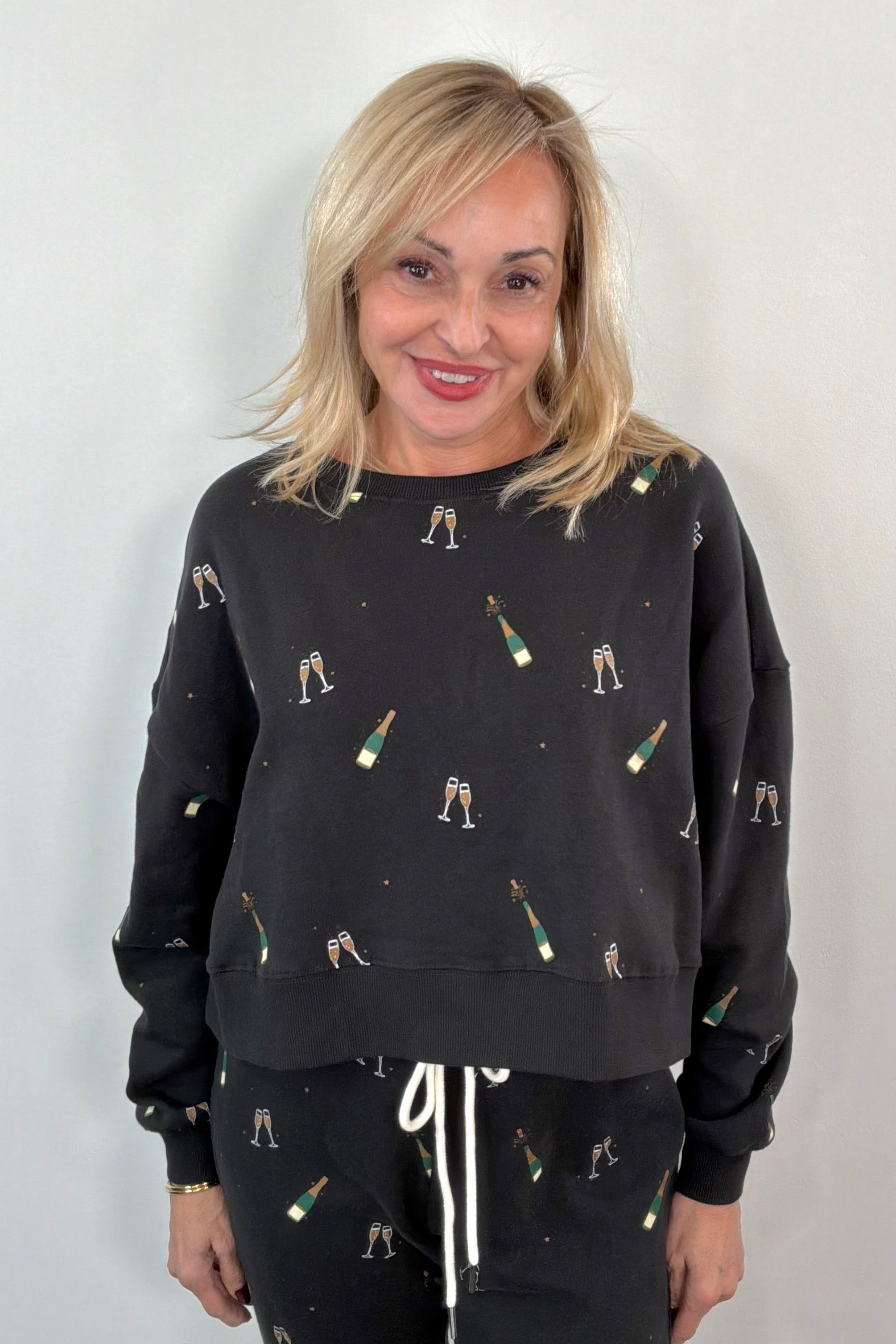 Woman wearing a black sweatshirt with champagne bottle print 