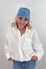 Woman wearing a light blue denim cap with “mother” stitched on the front