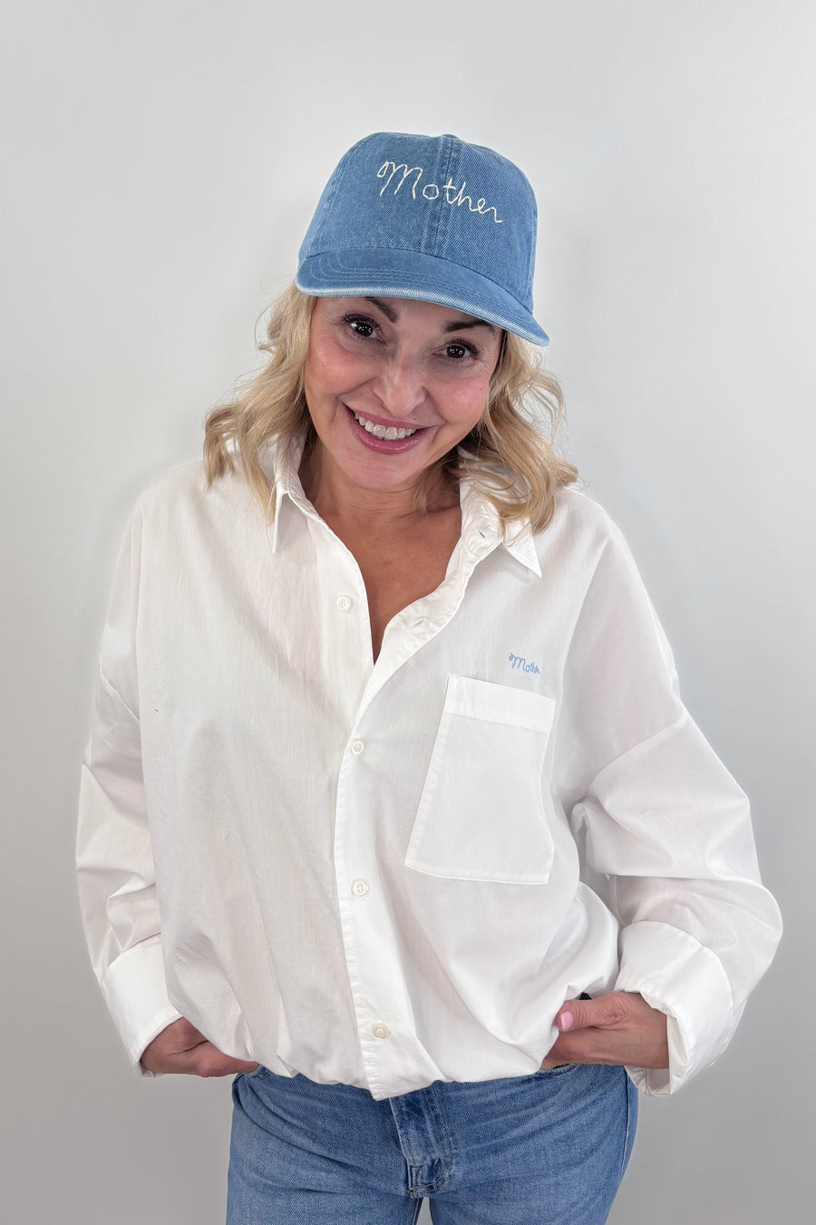 Woman wearing a light blue denim cap with “mother” stitched on the front