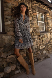 Front view of woman wearing a dress with a smocked elastic waist and neckline with black and white stripes 