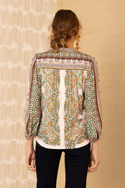 Back view of a woman wearing a patterned v-neck top with intricate and colourful designs.