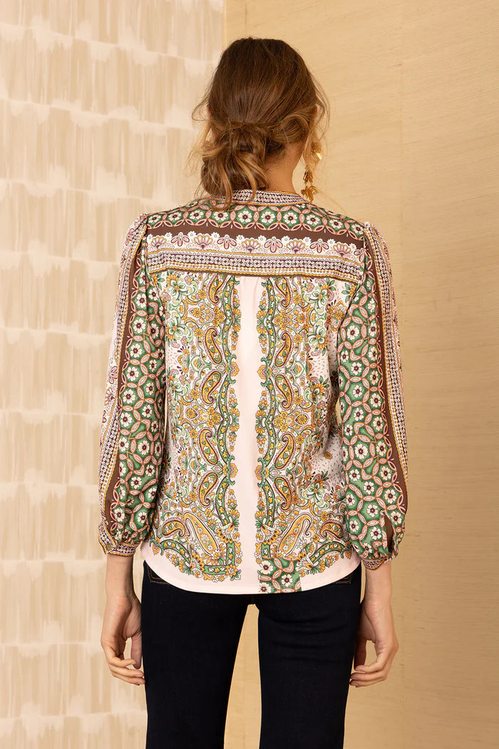 Back view of a woman wearing a patterned v-neck top with intricate and colourful designs.