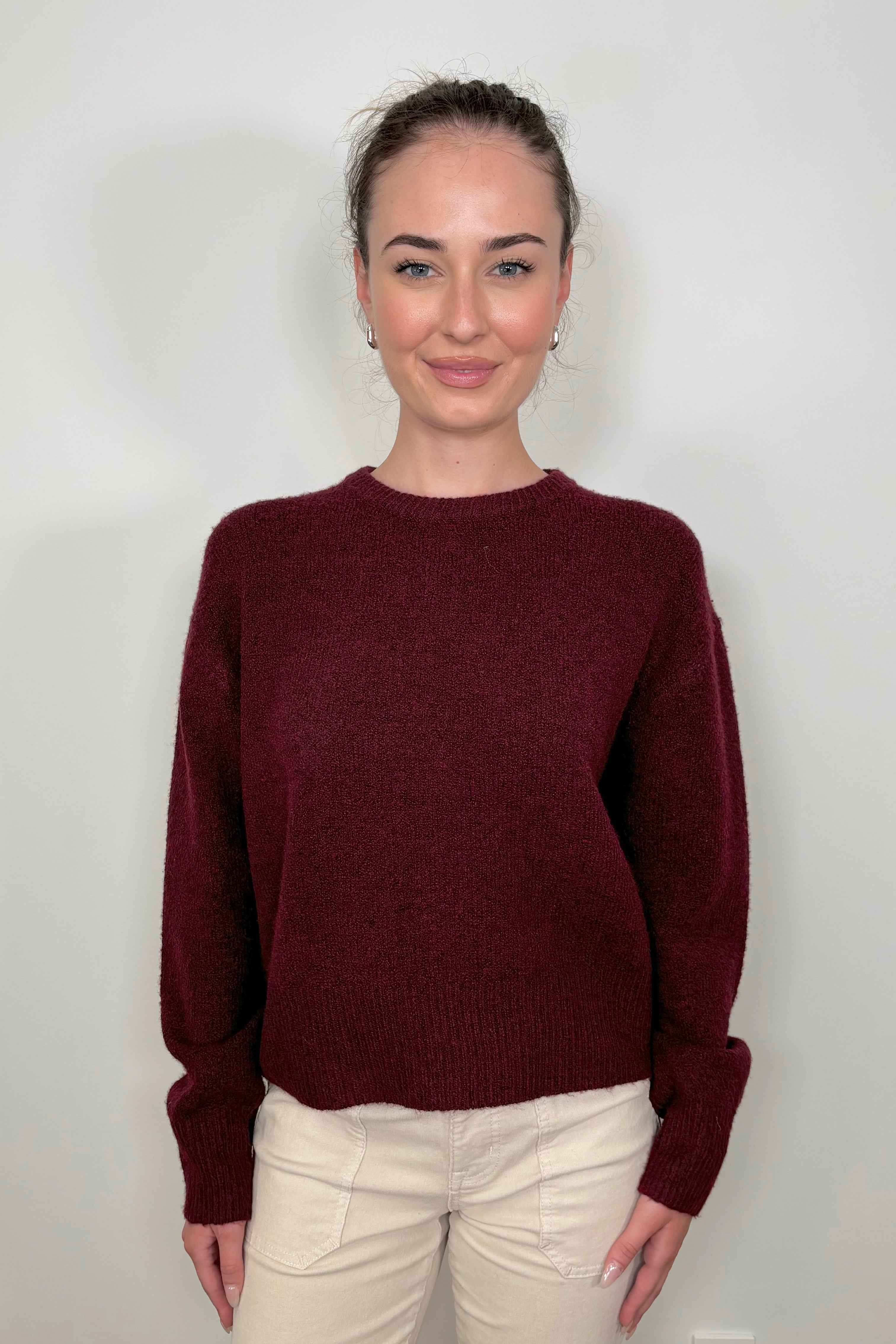 Front view of woman wearing a wine coloured crew-neck sweater 