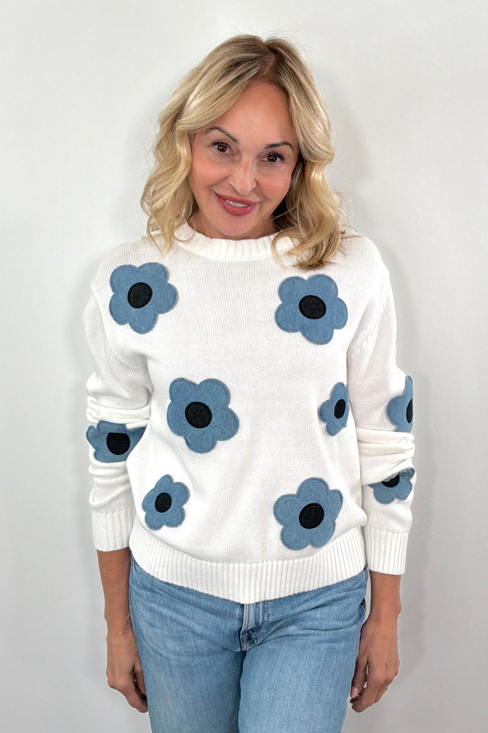 Woman wearing a while knit follower with denim floral design
