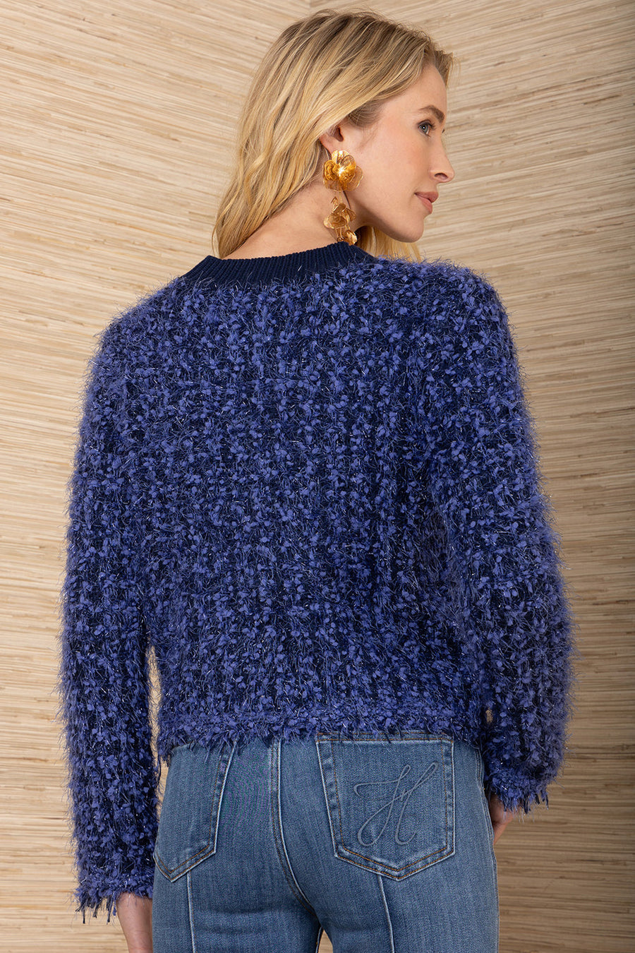 Woman wearing a blue textured sweater and jeans against a wooden background