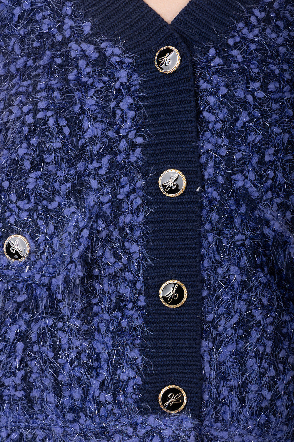 Close-up of a blue textured cardigan with gold buttons.
