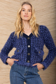 Woman wearing a blue knitted cardigan against a wooden background