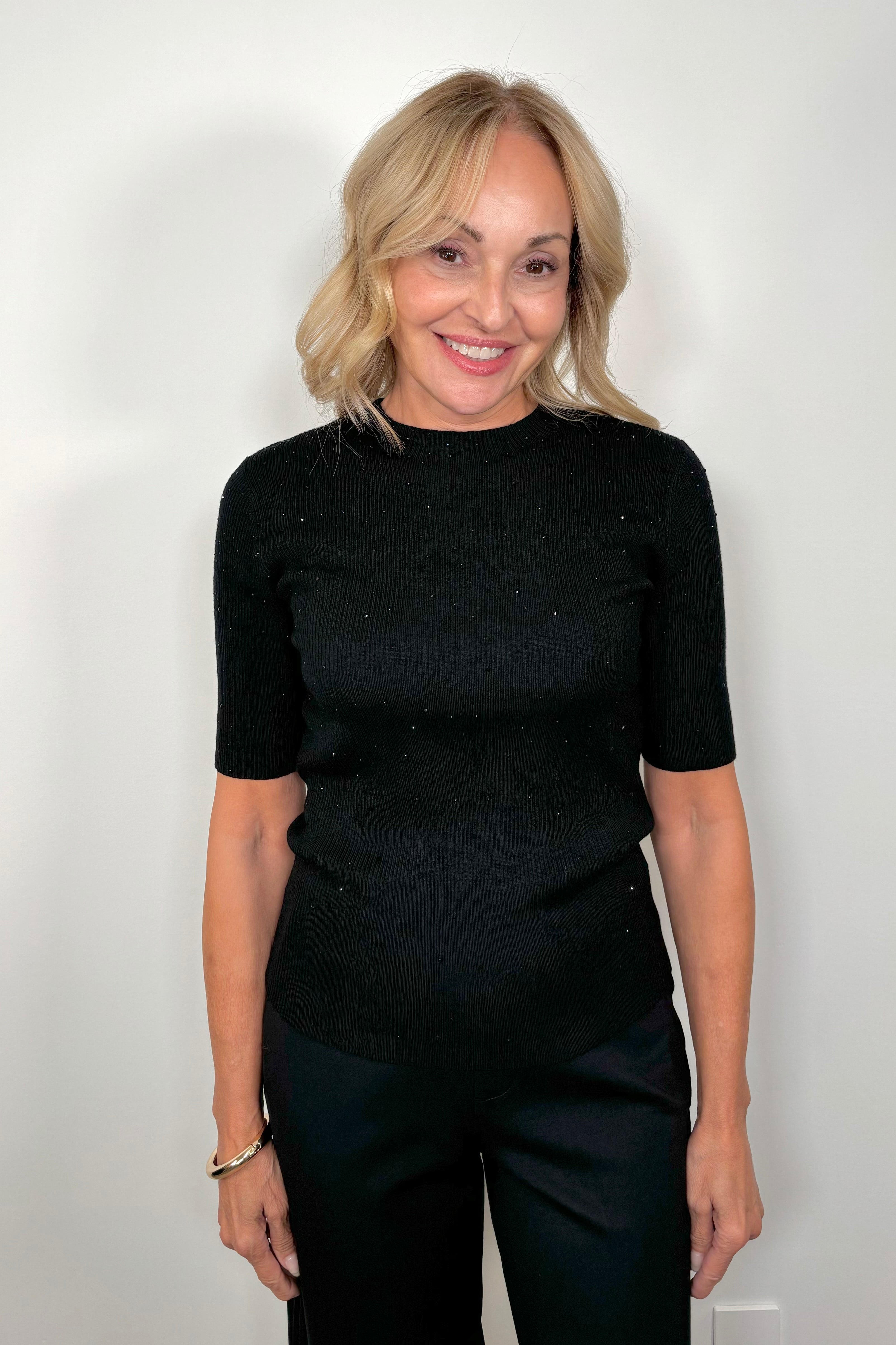 Front view of woman wearing a black ribbed tee with crystal embellishments 