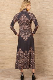 Woman wearing a long-sleeve, patterned dress against a wooden paneled wall.