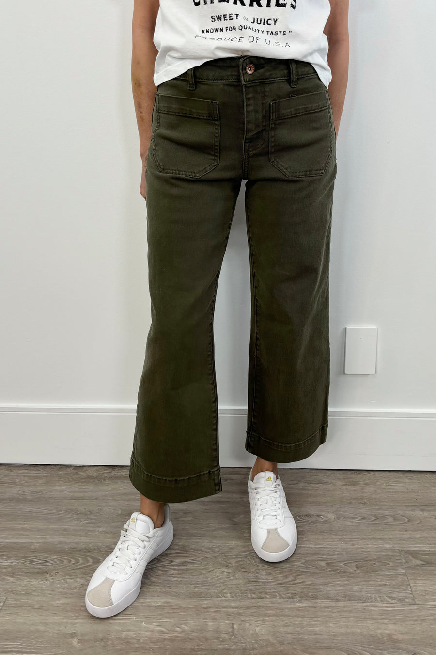 Woman wearing a dark green cropped flare denim with pockets on the front of the leg