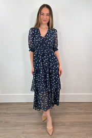 woman wearing a navy midi ruffle dress with white polka dots