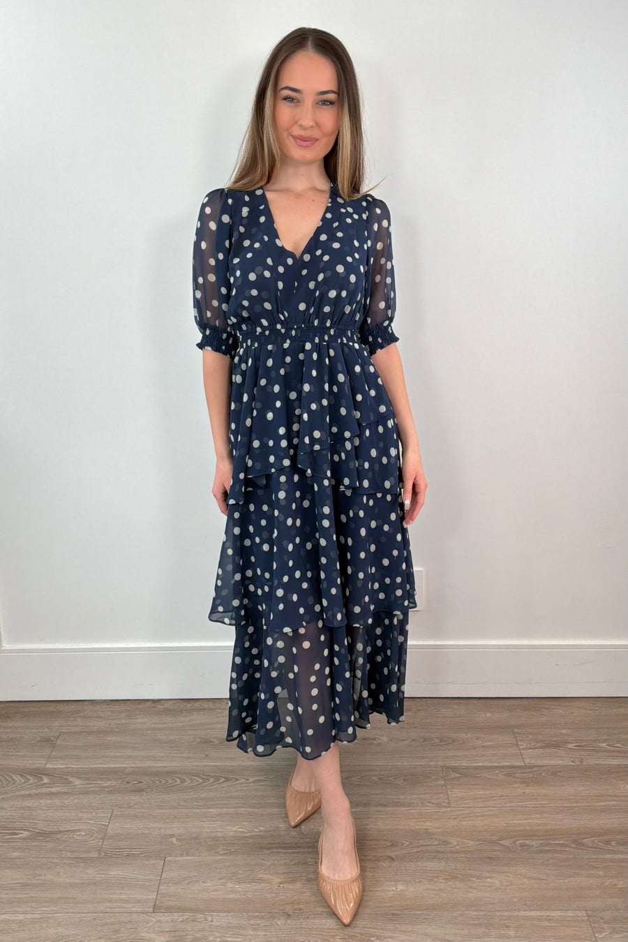 woman wearing a navy midi ruffle dress with white polka dots