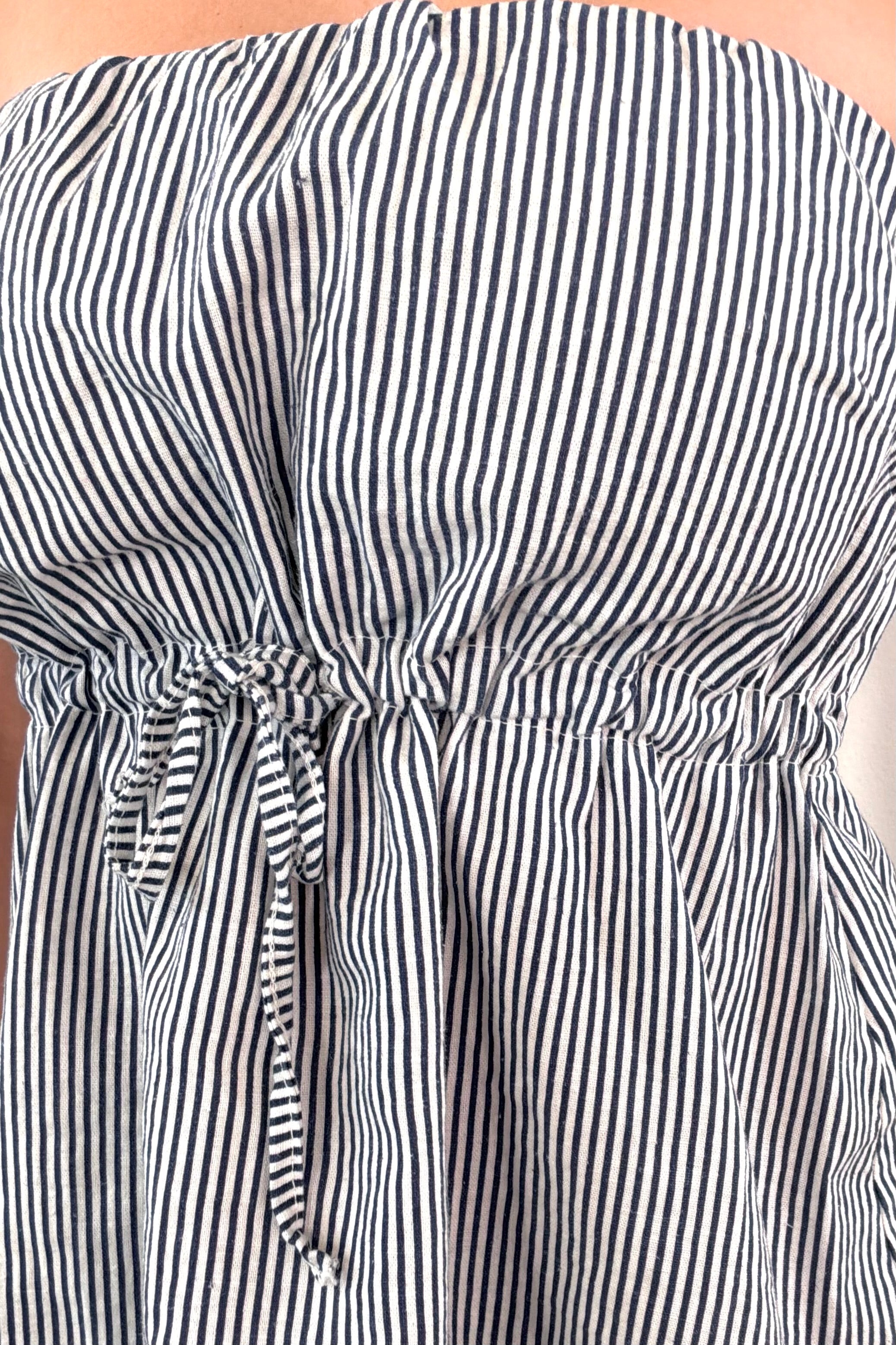 Close-up of the waist detail on a light, blue and white striped strapless top