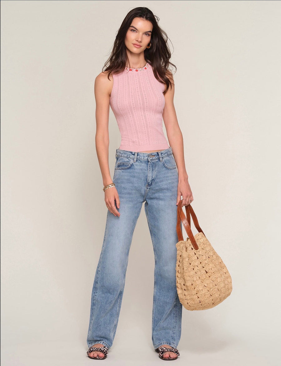 Woman wearing a ballet pink knit tank top with embroidered floral print around the neckline