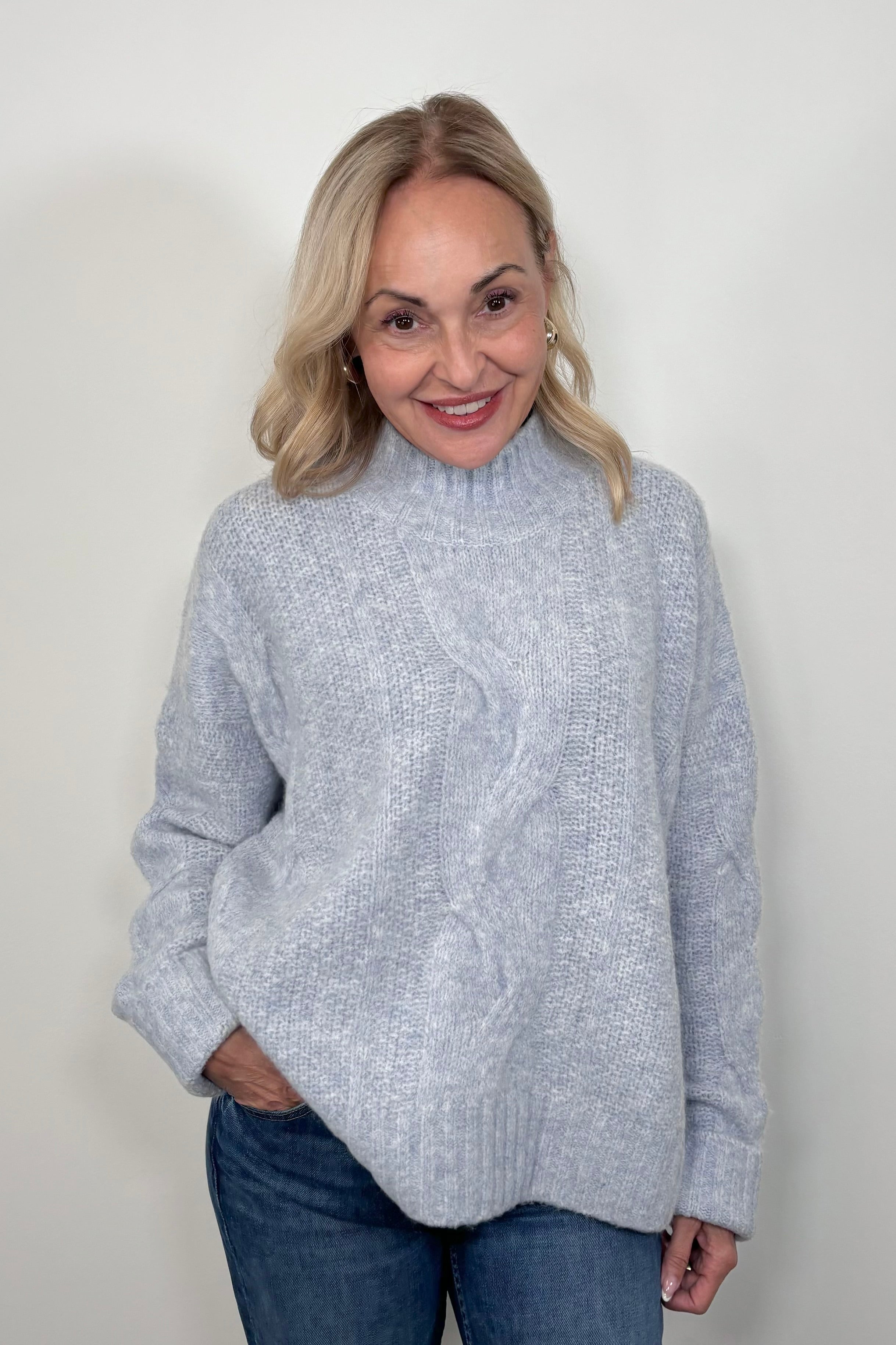 Front view of woman wearing a high neck light blue knitted sweater 