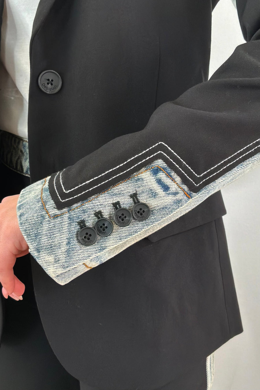Close up of cuffs of Woman wearing a mixed denim fabric blazer in black and hints of light blue