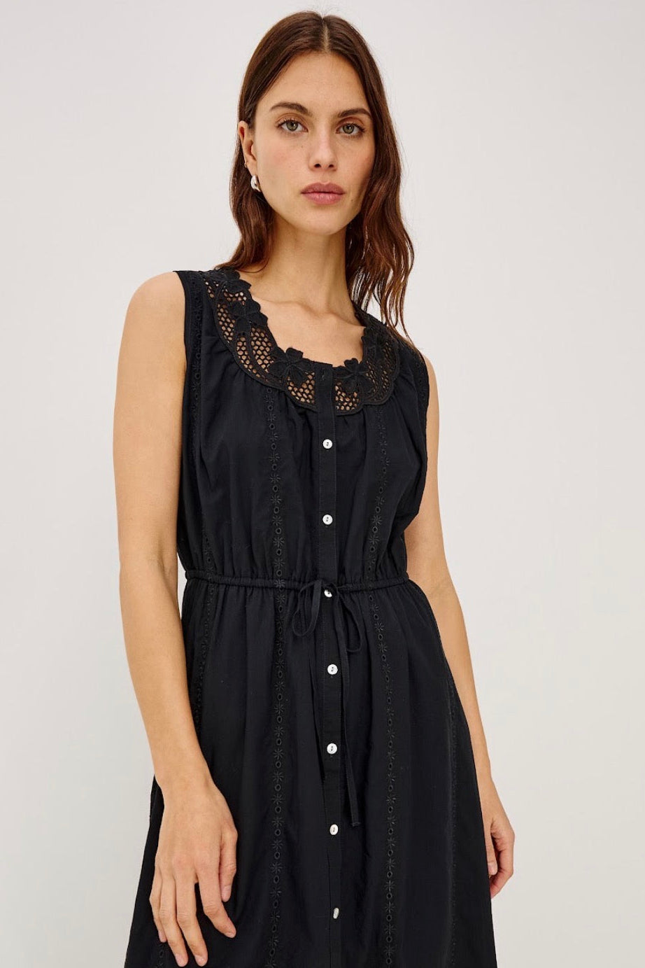 Close up of Woman wearing a black button up dress with embroidery detail