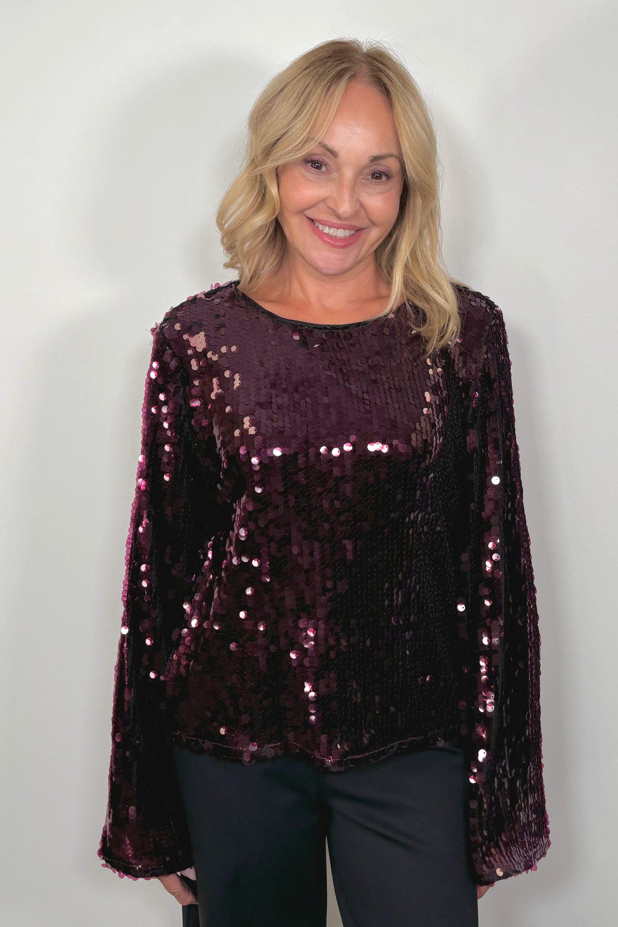 woman wearing a maroon sequin long flared sleeves top