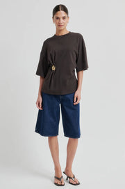 Woman wearing a brown short-sleeve crewneck top with a side ring detail, front