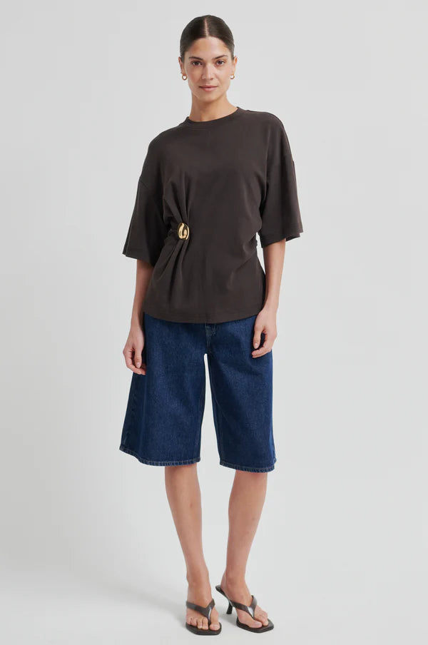 Woman wearing a brown short-sleeve crewneck top with a side ring detail, front