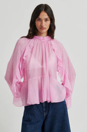 Pink long-sleeve blouse with ruffle details, high neckline, and flowy silhouette, front