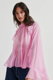 Pink long-sleeve blouse with ruffle details, high neckline, and flowy silhouette, front