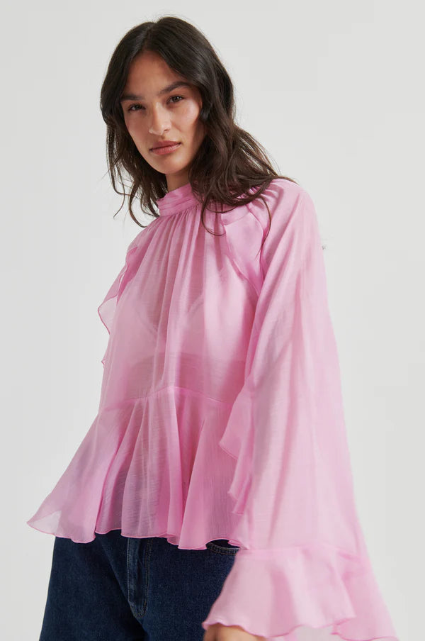 Pink long-sleeve blouse with ruffle details, high neckline, and flowy silhouette, front