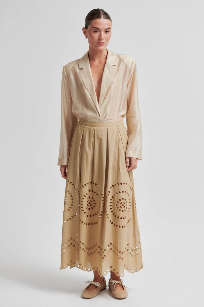 Woman wearing a beige midi skirt with embroidery details and concealed side pockets