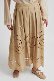 Woman wearing a beige midi skirt with embroidery details and concealed side pockets