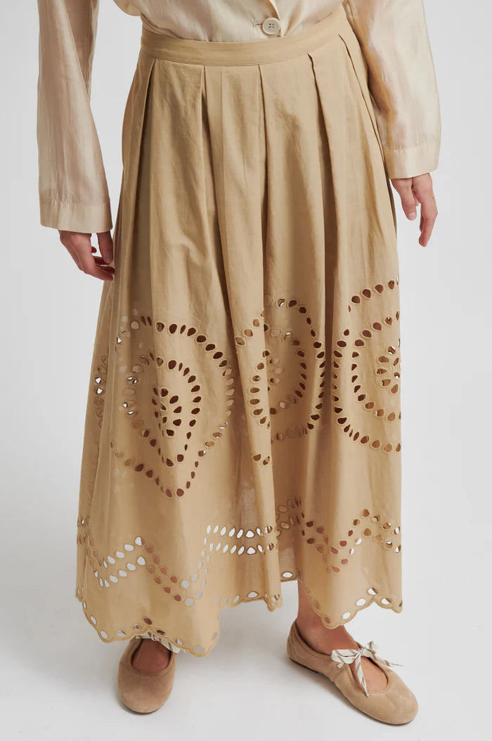 Woman wearing a beige midi skirt with embroidery details and concealed side pockets