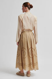 Woman wearing a beige midi skirt with embroidery details and concealed side pockets