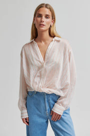 Woman wearing a light-colored striped shirt with a twisted hem and regular collar 