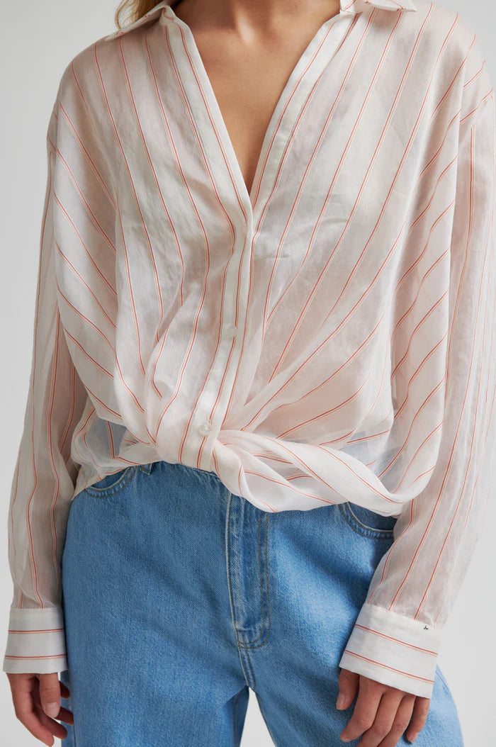 Woman wearing a light-colored striped shirt with a twisted hem and regular collar 