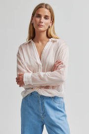 Woman wearing a light-colored striped shirt with a twisted hem and regular collar 