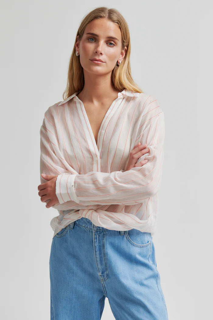 Woman wearing a light-colored striped shirt with a twisted hem and regular collar 