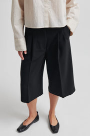 Woman wearing oversized black Bermuda shorts with pockets