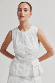 Woman wearing a white sleeveless round neck top with 3D mesh floral details