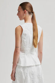 Woman wearing a white sleeveless round neck top with 3D mesh floral details