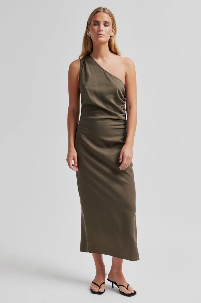 Woman wearing a one-shoulder olive green dress with ruched detail. 