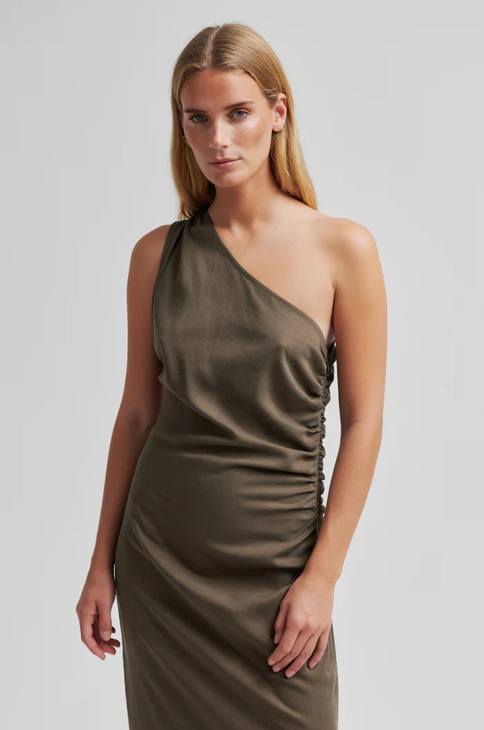 Woman wearing a one-shoulder olive green dress with ruched detail. 