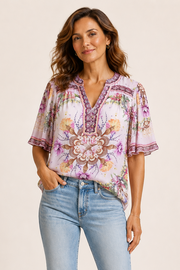 Woman wearing a pink floral blouse with a detailed shell pattern and 3/4 sleeves 