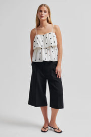 Woman wearing a lightweight linen-viscose white top with black polka dots