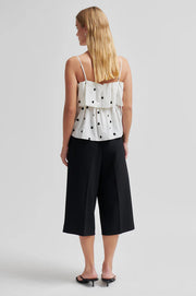 Woman wearing a lightweight linen-viscose white top with black polka dots 