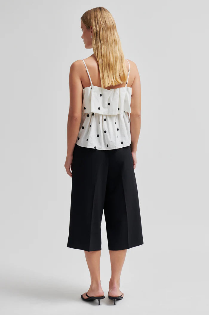 Woman wearing a lightweight linen-viscose white top with black polka dots 