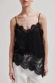 Woman wearing a asymmetrical black lace-trimmed top 