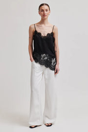 Woman wearing a asymmetrical black lace-trimmed top 